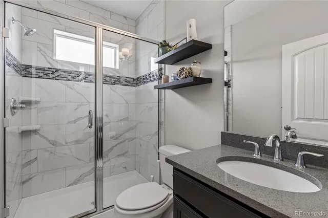 a bathroom with a granite countertop sink toilet a mirror and shower