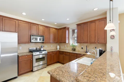 a kitchen with stainless steel appliances granite countertop a sink stove and refrigerator
