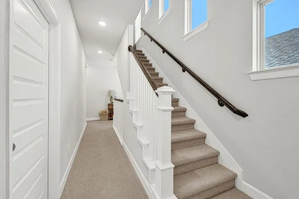 a view of staircase with lots of frames on wall and a window