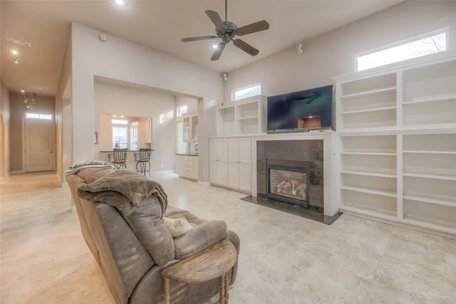 an empty room with chandelier fan and windows