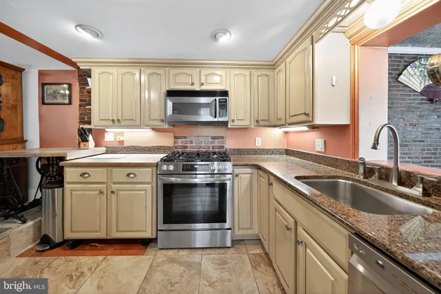 a kitchen with stainless steel appliances granite countertop a stove a sink and a microwave