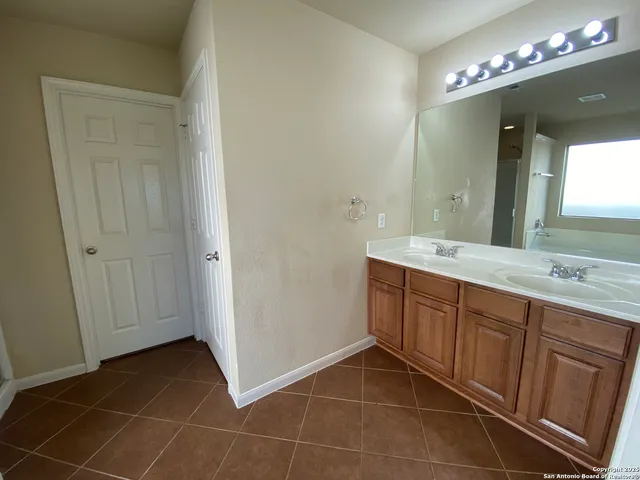 a spacious bathroom with a double vanity sink a mirror and a shower