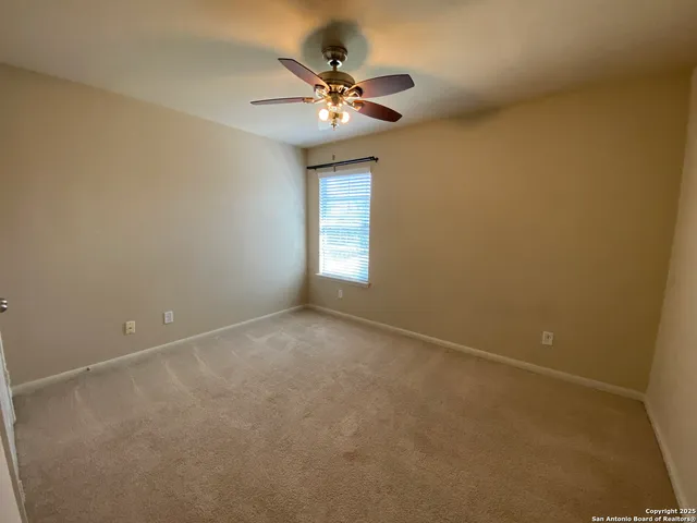 an empty room with a chandelier fan and windows