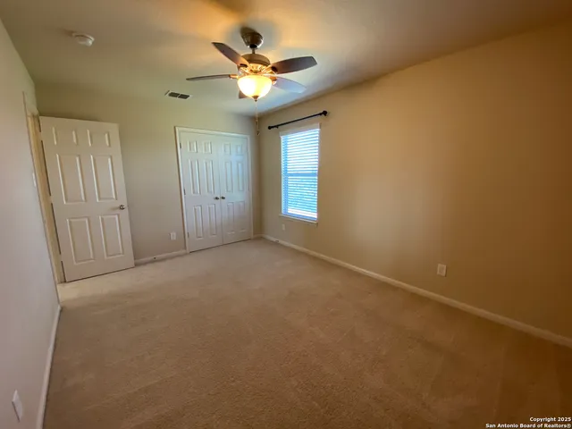 an empty room with a chandelier fan and windows