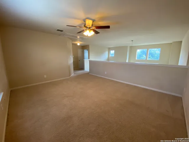 an empty room with a chandelier fan and windows