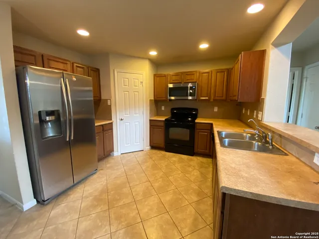 a kitchen with stainless steel appliances granite countertop a refrigerator a stove and a sink