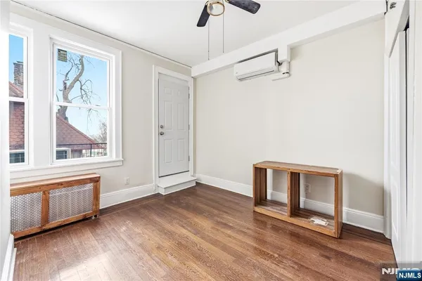 a view of an empty room with a window and wooden floor
