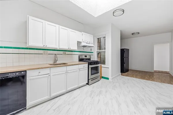 a kitchen with granite countertop a sink stainless steel appliances and cabinets
