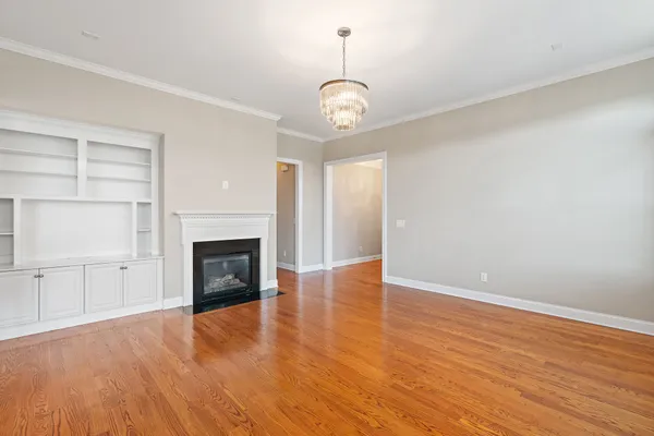 an empty room with wooden floor fireplace and windows