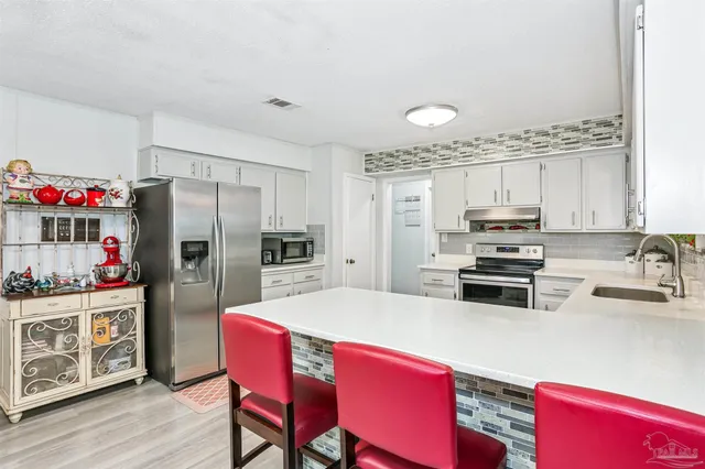 a kitchen with stainless steel appliances a refrigerator sink stove dining table and chairs