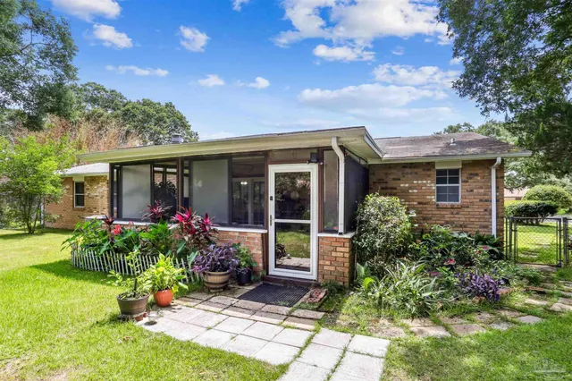 a view of house with a yard and potted plants