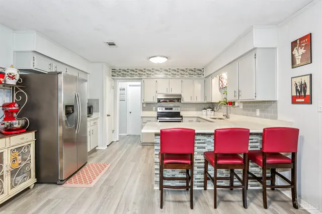 a kitchen with stainless steel appliances a dining table chairs and wooden floor