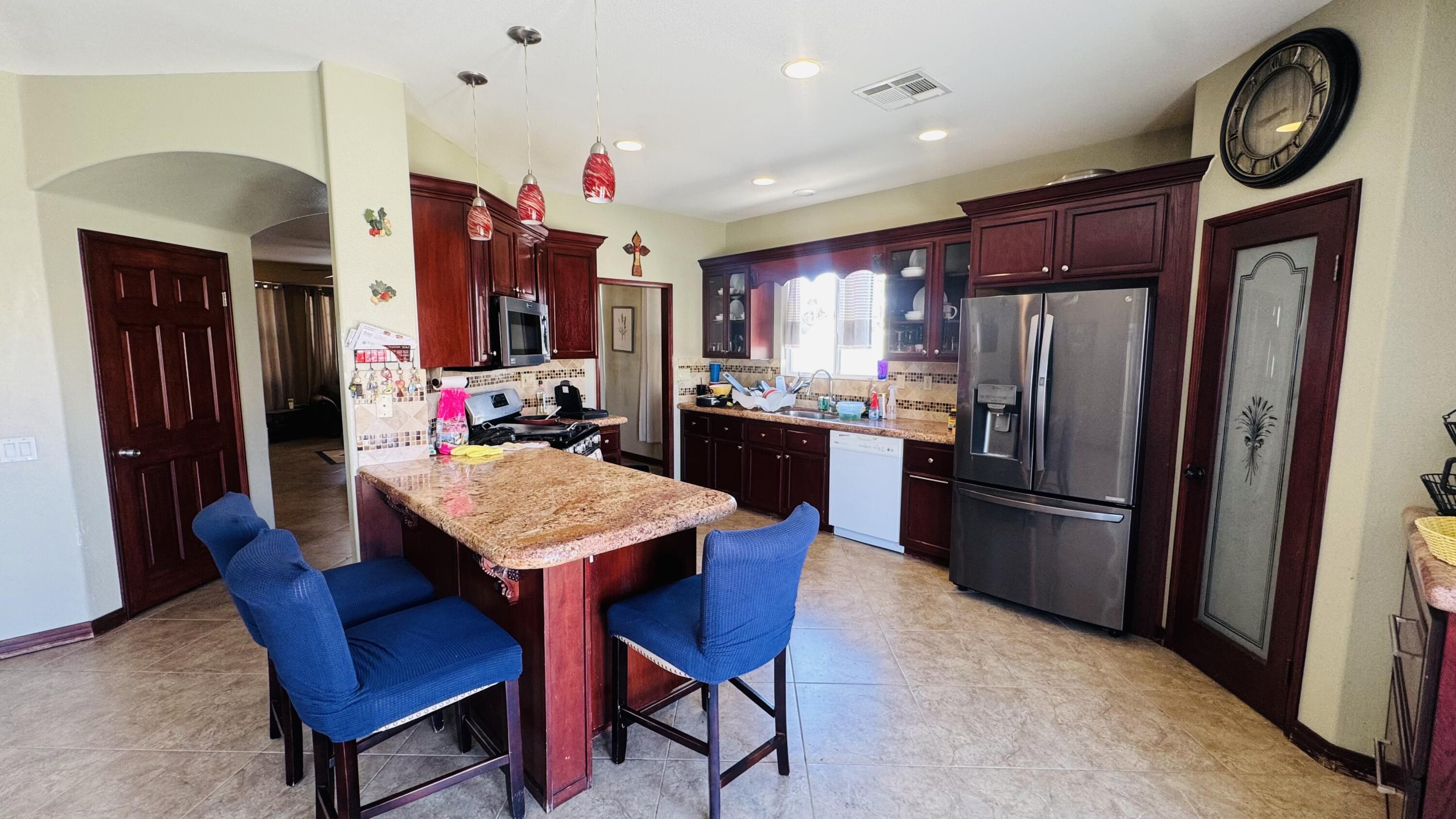 47818 Phoenix Street Indio, CA 92201 - Photo 3 of 14 a kitchen with stainless steel appliances granite countertop a dining table chairs refrigerator and stove