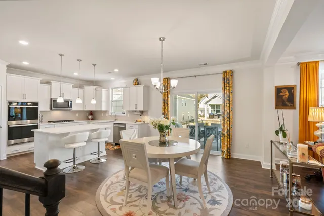 a view of a dining room and livingroom with furniture wooden floor a chandelier
