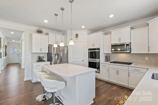 a large kitchen with kitchen island a refrigerator a stove a dining table and chairs with wooden floor