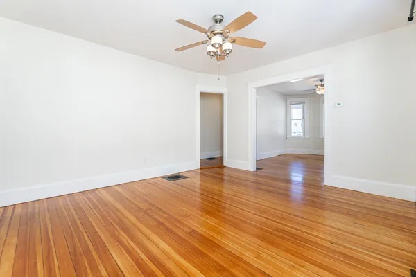 an empty room with wooden floor and a ceiling fan