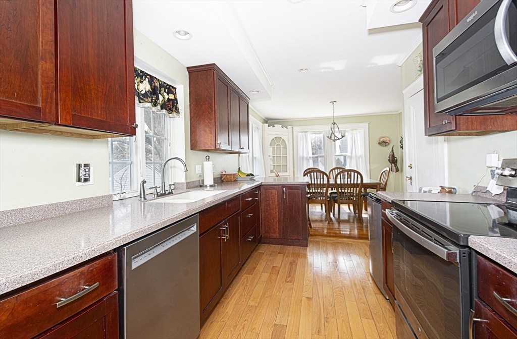 15 Monroe Street Shrewsbury, MA 01545 - Photo 11 of 30 a kitchen with stainless steel appliances granite countertop wooden cabinets a sink dishwasher a stove and a refrigerator with wooden floor
