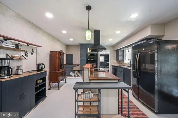 a kitchen with stainless steel appliances kitchen island granite countertop a refrigerator a stove and a sink