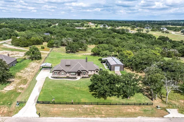 an aerial view of residential houses with outdoor space and trees
