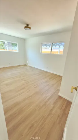 a view of empty room with window and wooden floor
