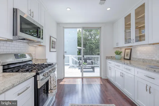 a kitchen with stainless steel appliances granite countertop a stove a sink and white cabinets with wooden floor