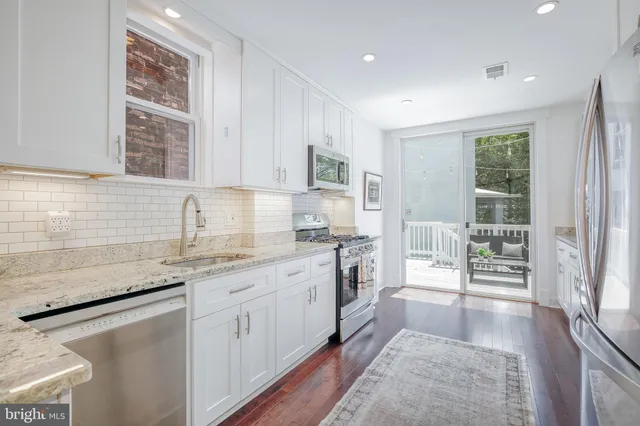 a kitchen with granite countertop white cabinets and a sink