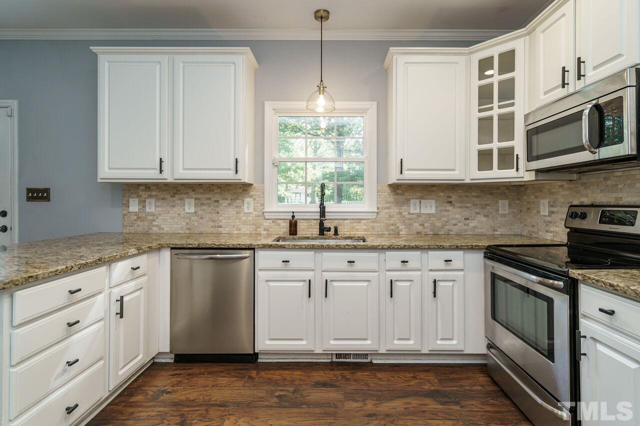 4202 Holt School Road Durham, NC 27704 - Photo 13 of 27 a kitchen with stainless steel appliances granite countertop a stove a sink and a microwave