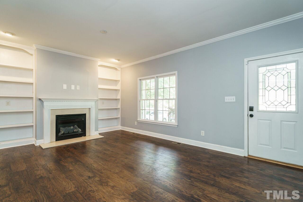 4202 Holt School Road Durham, NC 27704 - Photo 3 of 27 a view of an empty room with wooden floor fireplace and a window