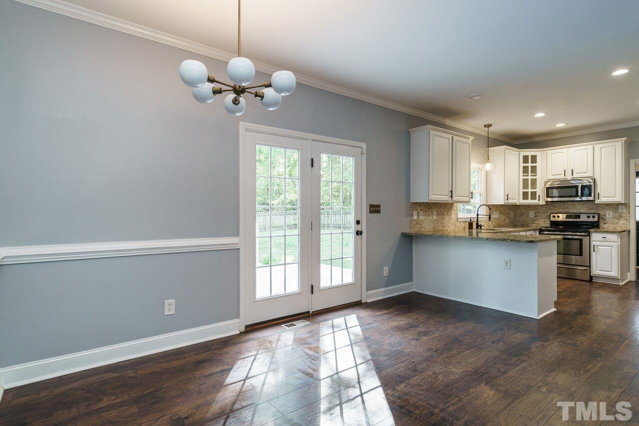 4202 Holt School Road Durham, NC 27704 - Photo 9 of 27 a kitchen with stainless steel appliances granite countertop a stove a refrigerator a sink a dishwasher with wooden floor and cabinets