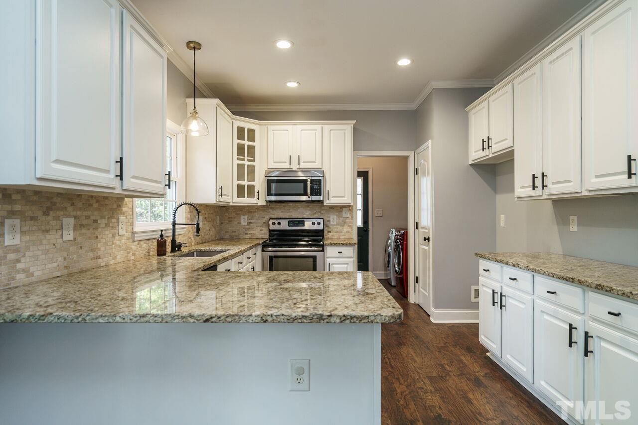 4202 Holt School Road Durham, NC 27704 - Photo 10 of 27 a kitchen with kitchen island granite countertop a sink stove and cabinets