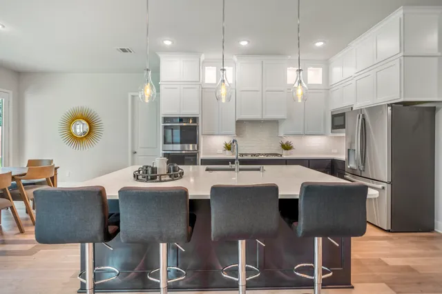 a kitchen with stainless steel appliances granite countertop a refrigerator a stove a sink dishwasher a dining table and chairs with wooden floor