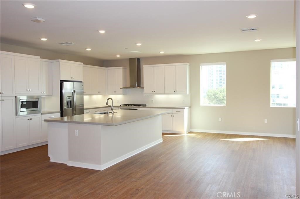 186 Tribeca Irvine, CA 92612 - Photo 5 of 25 a kitchen with stainless steel appliances granite countertop a sink a stove a refrigerator cabinets and a wooden floor