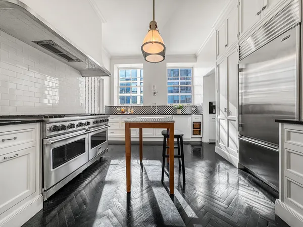 a kitchen with stainless steel appliances granite countertop a stove a sink dishwasher and white cabinets with wooden floor