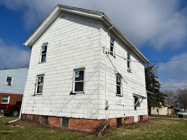 a view of house with backyard and trees in the background
