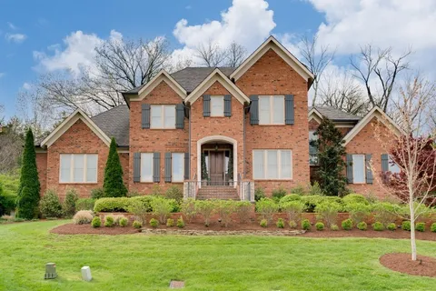 a front view of a house with a yard and potted plants