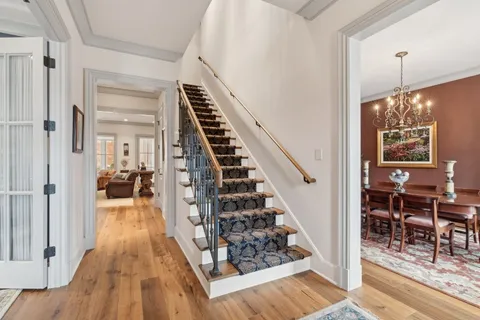 a view of a hallway to a livingroom with wooden floor and stairs