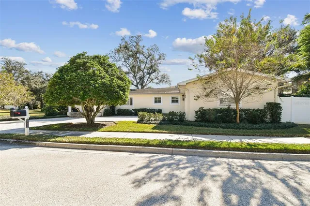 a view of a white house with a big yard and large trees