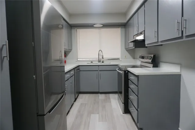 a kitchen with a sink a stove cabinets and a window