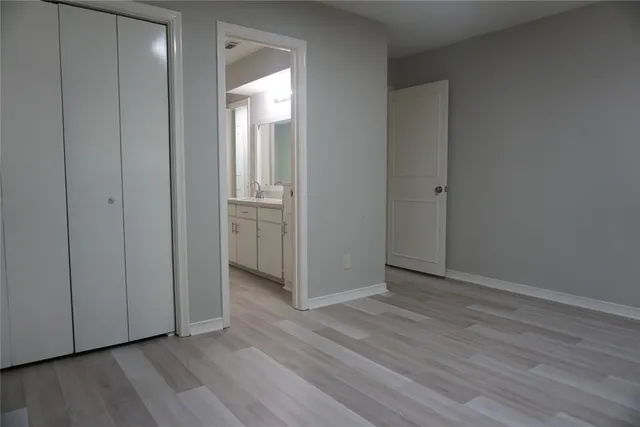 a view of an empty room with wooden floor and closet