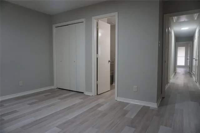 a view of an empty room with wooden floor and a mirror