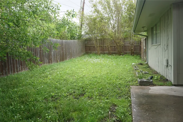 a view of a backyard with plants and wooden fence