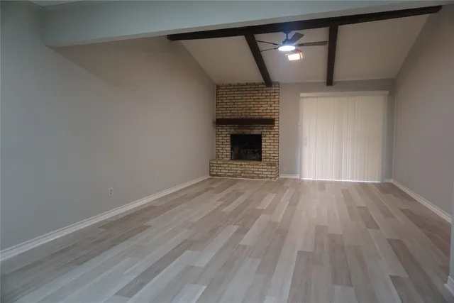 a view of empty room with wooden floor and fireplace