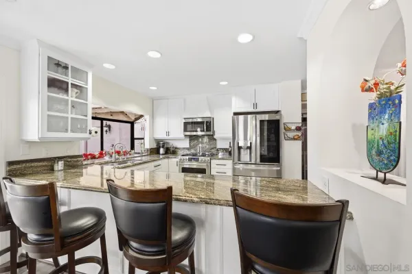 a kitchen with granite countertop stainless steel appliances a stove sink and refrigerator