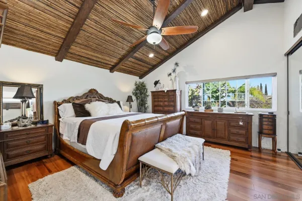 a bedroom with a bed and a large mirror on the dresser