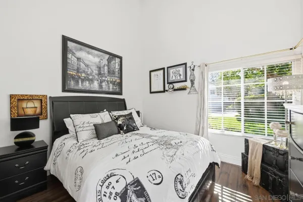 a bedroom with a bed and dresser with wooden floor