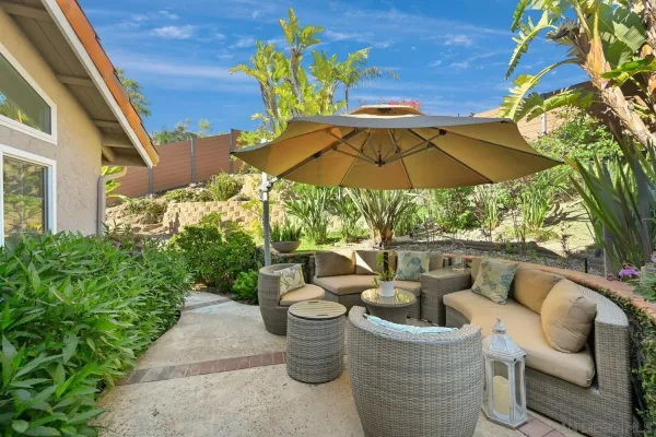 a view of a patio with couches table and chairs under an umbrella