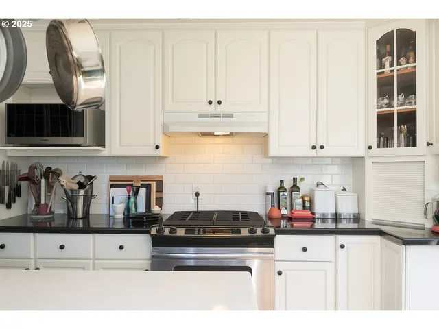 a kitchen with stainless steel appliances granite countertop a stove a sink and white cabinets