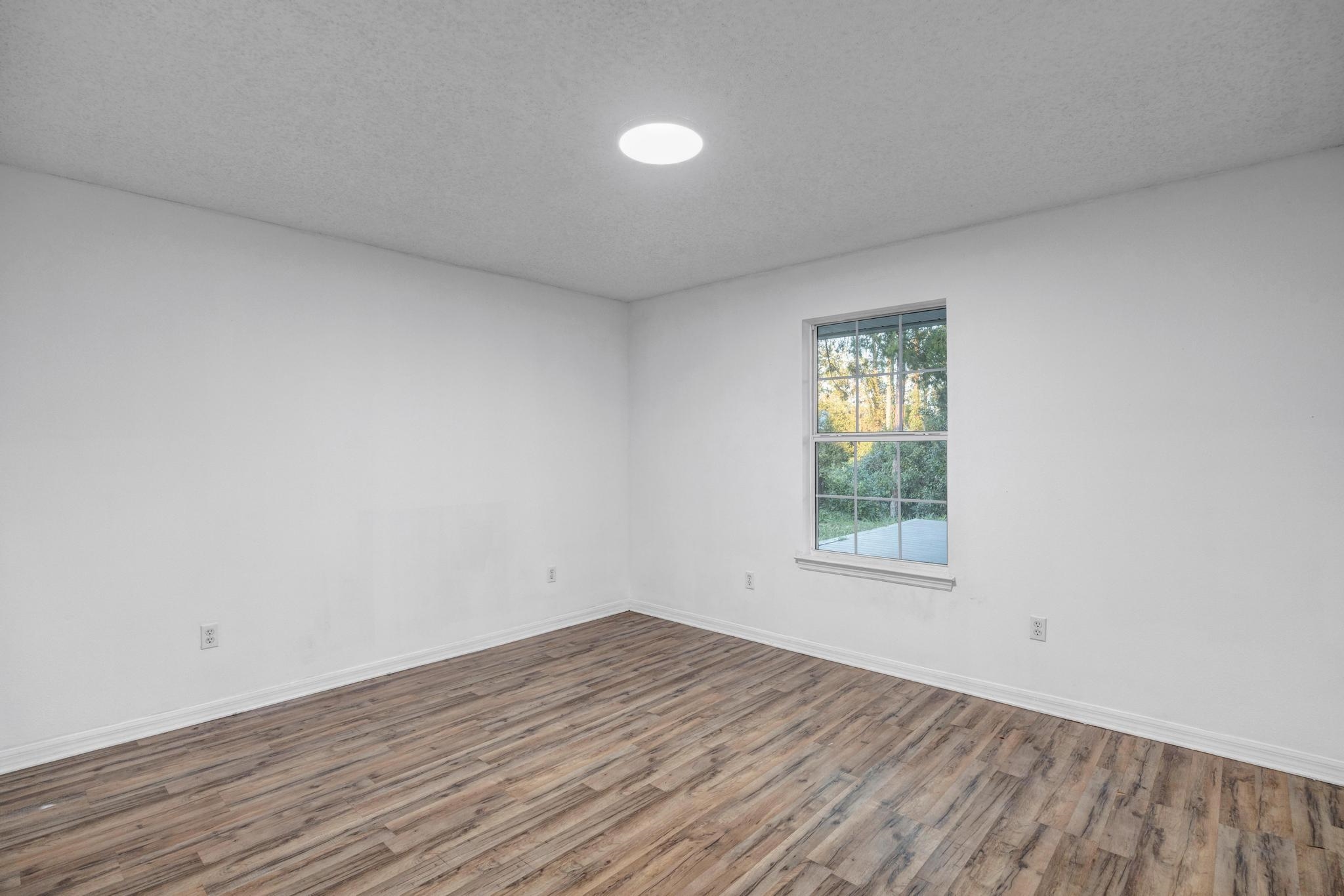 98 Roxboro Drive Palm Coast, FL 32164 - Photo 23 of 28 an empty room with wooden floor and windows