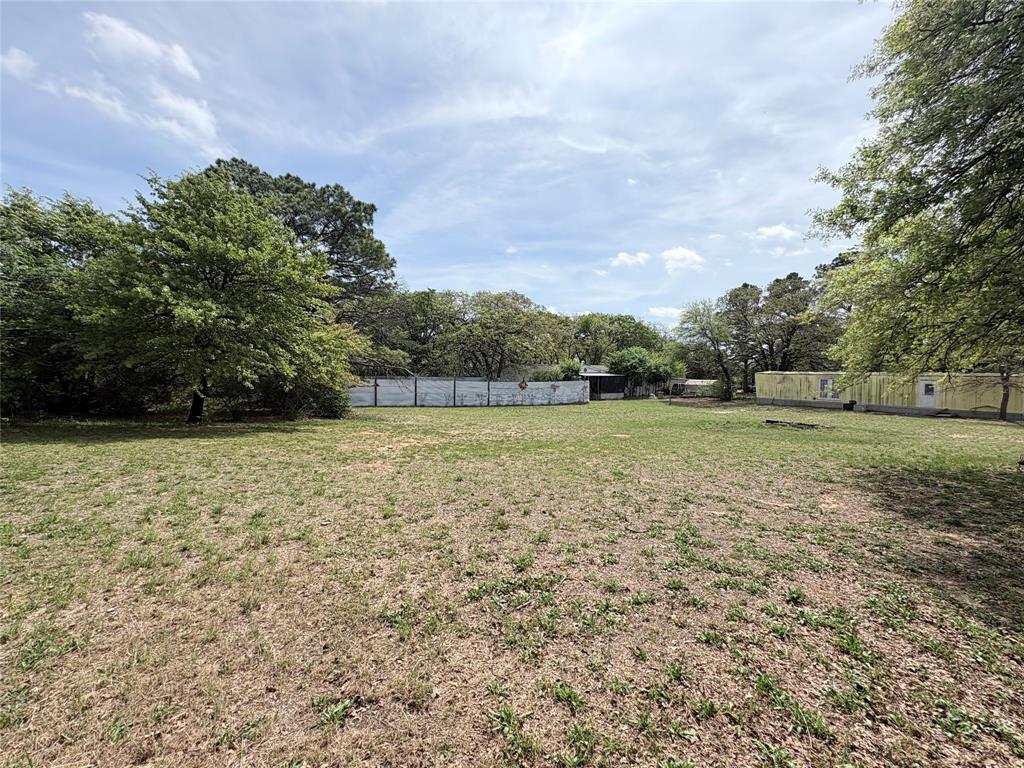 6295 Rendon New Hope Road Fort Worth, TX 76140 - Photo 36 of 38 Expansive grassy parcel featuring mature trees, a perimeter fence, and visible sky