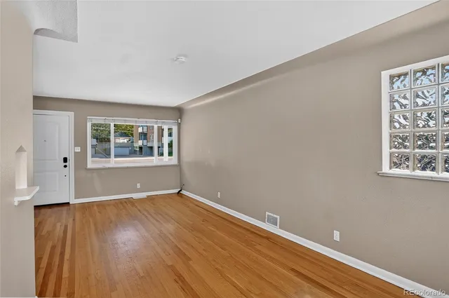 an empty room with wooden floor and windows